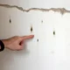 persoana indică locația exactă a umidității pe perete